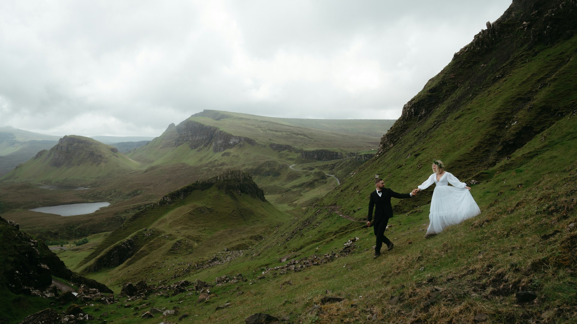 Brautpaar Hand in Hand auf grünem Hügel — Hochzeit in Bayern